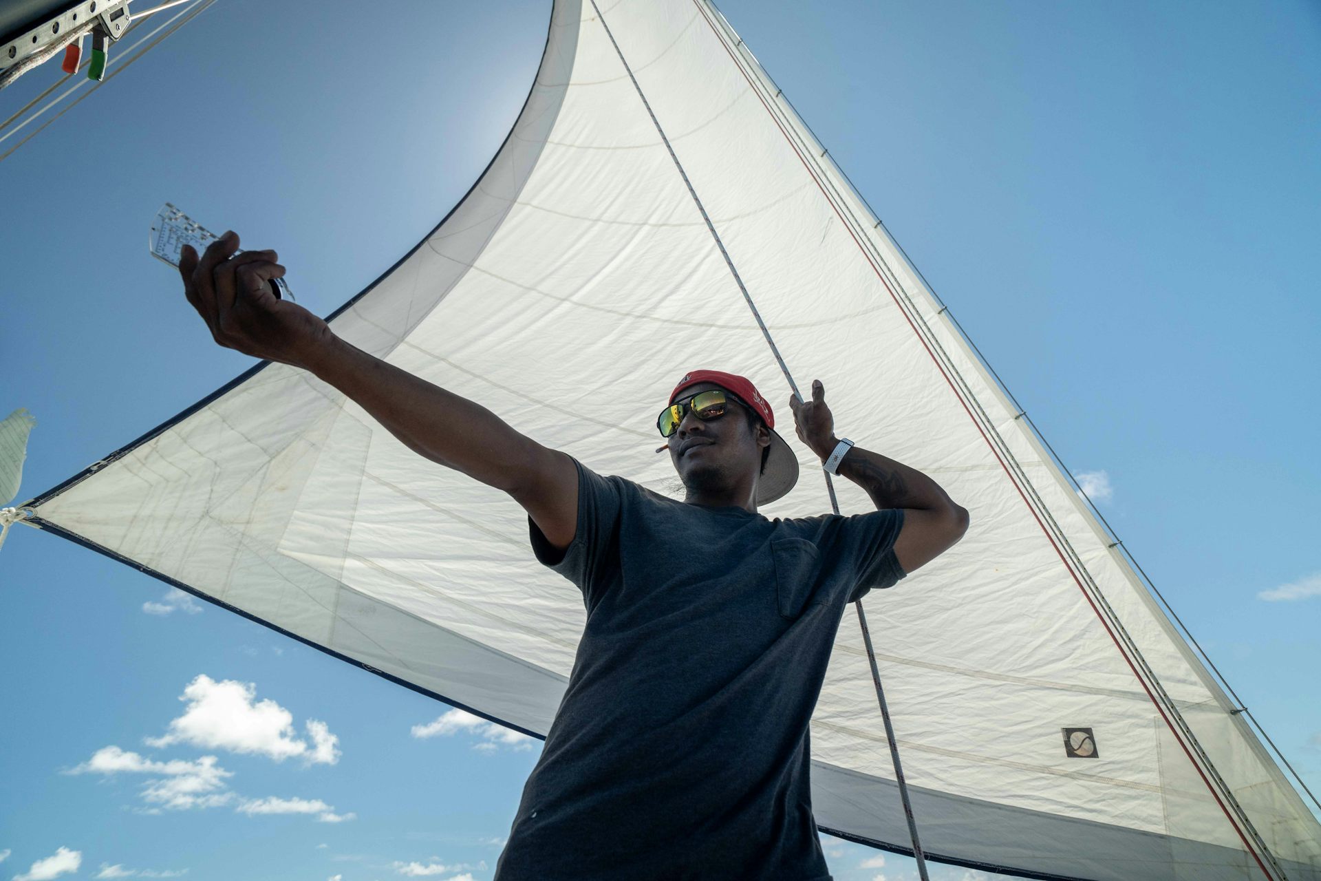 sailor pointing to sea, white sail, blue sky