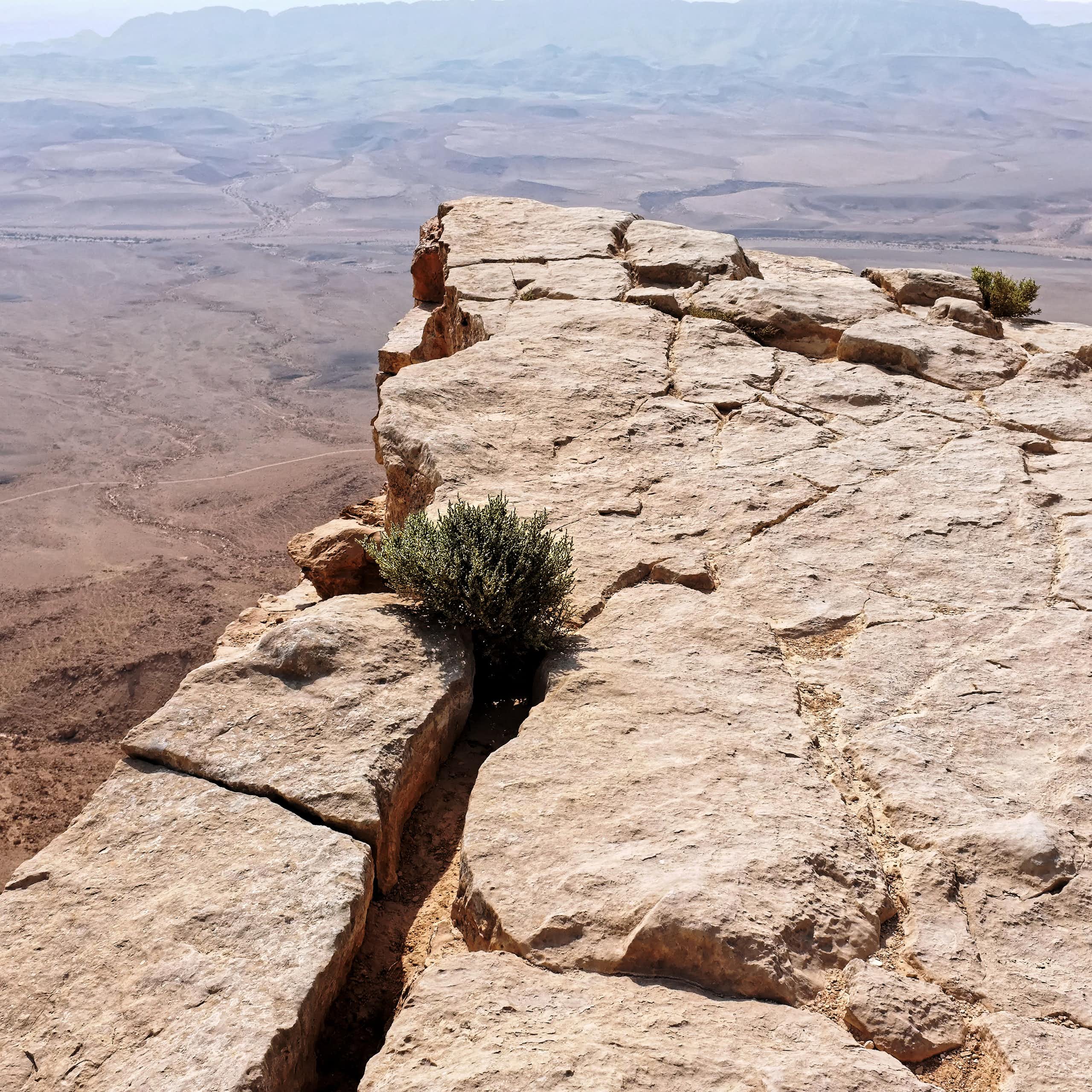 a far horizon can be seen in the desert at the edge of a high cliff that juts out