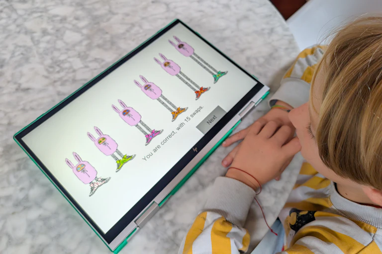 child with tablet with four cartoon creatures of various heights