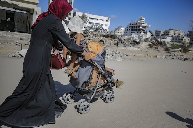 A Palestinian mother flees with her children following an Israeli airstrike during an October Israeli military operation in Gaza.