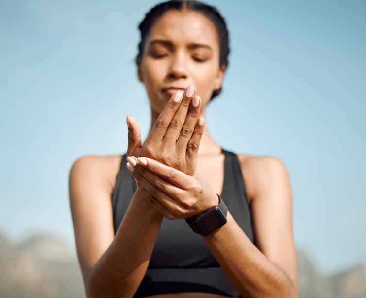 A young woman holds her hand in pain.