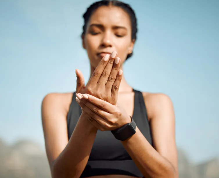 A young woman holds her hand in pain.