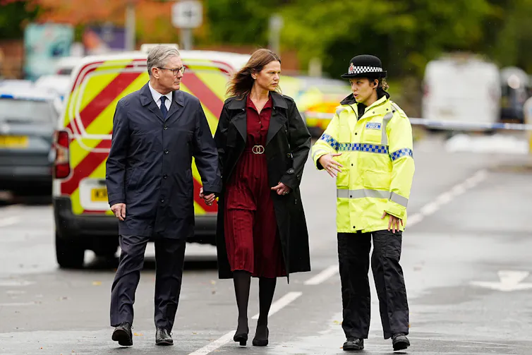 Keir Starmer and his wife talking to a police officer in a cordoned off area.