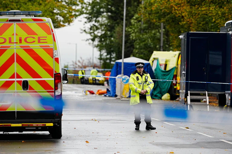 A police officer standing in a cordoned-off street.