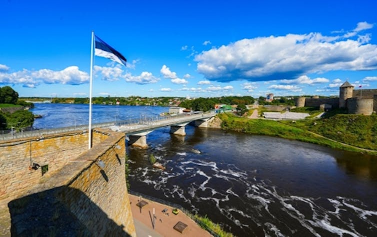 An overhead shot of the Narva bridge in Estonia with the national flag in the foreground.