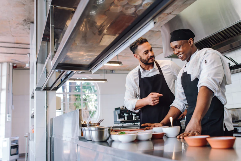 young restaurant worker in a kitchen with an older boss