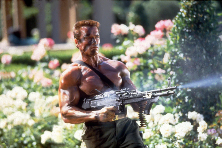 Schwarzenegger shooting a gun in a garden