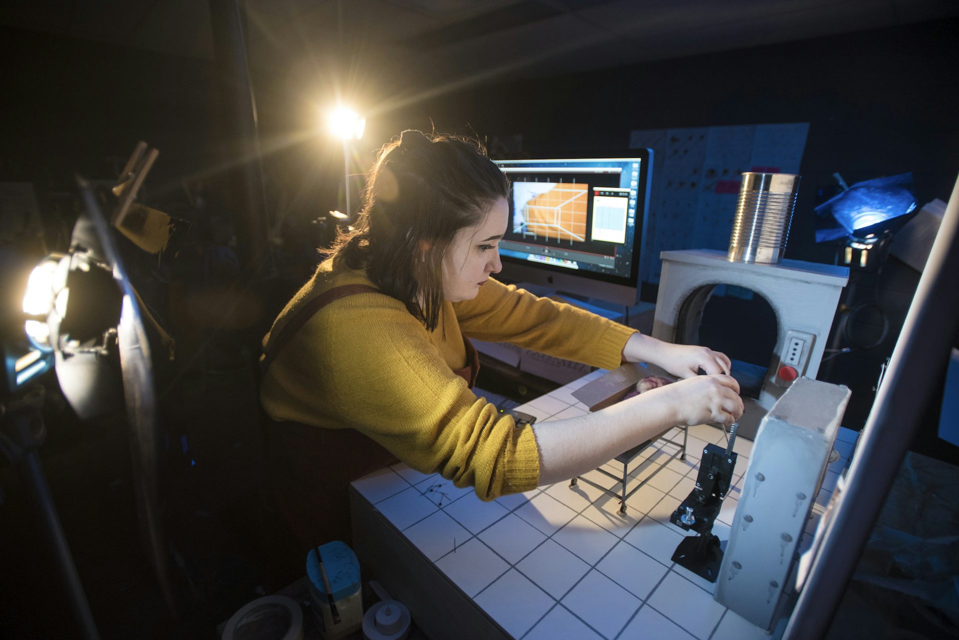 La persona vista con el equipo técnico y de pantalla, contra la habitación oscura.