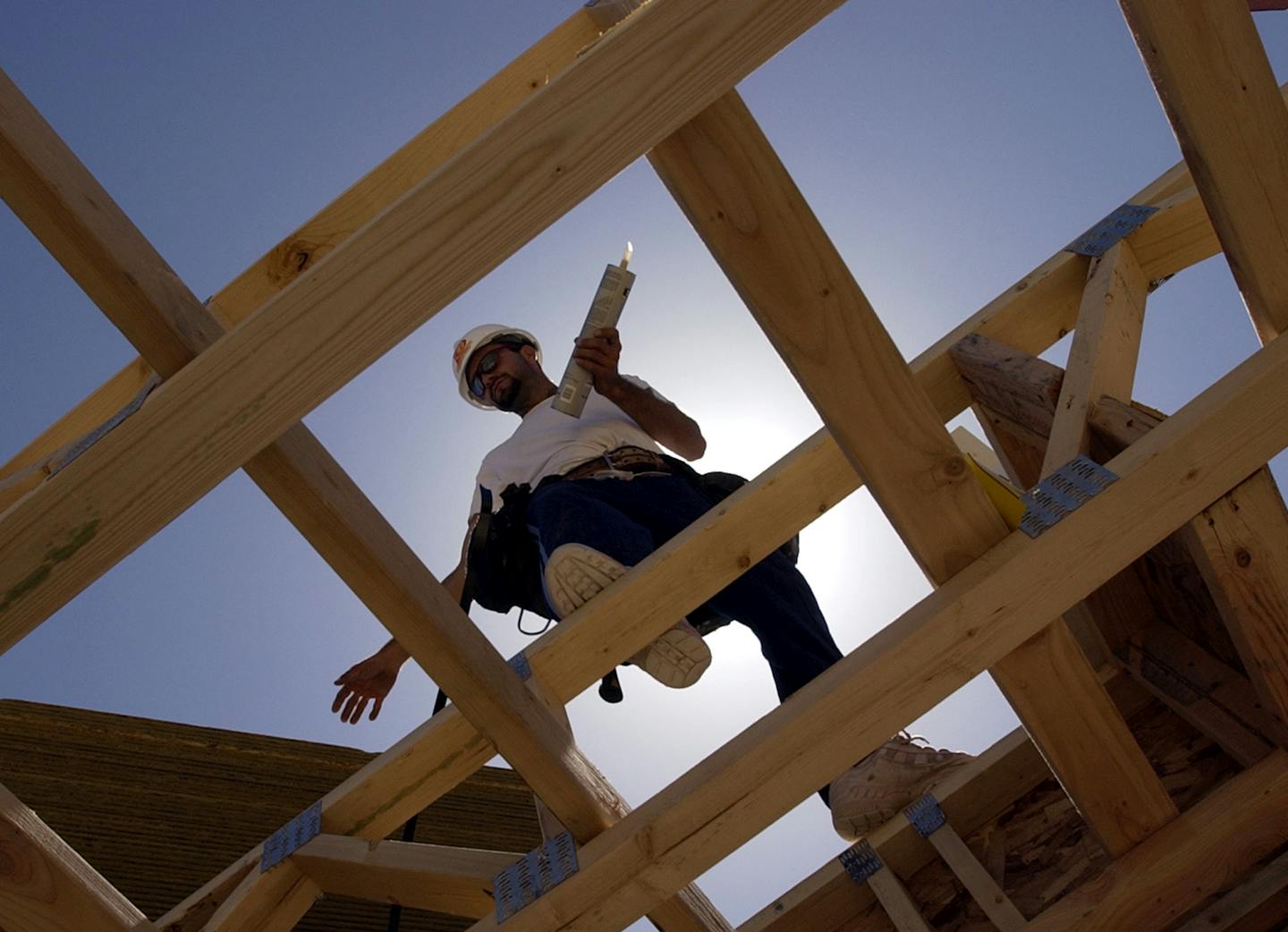 A construction worker walks in the frame of a house.