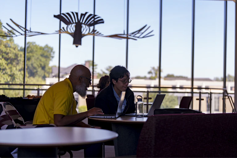 Two people looking at a laptop at the launch of new AI research center in North Carolina.