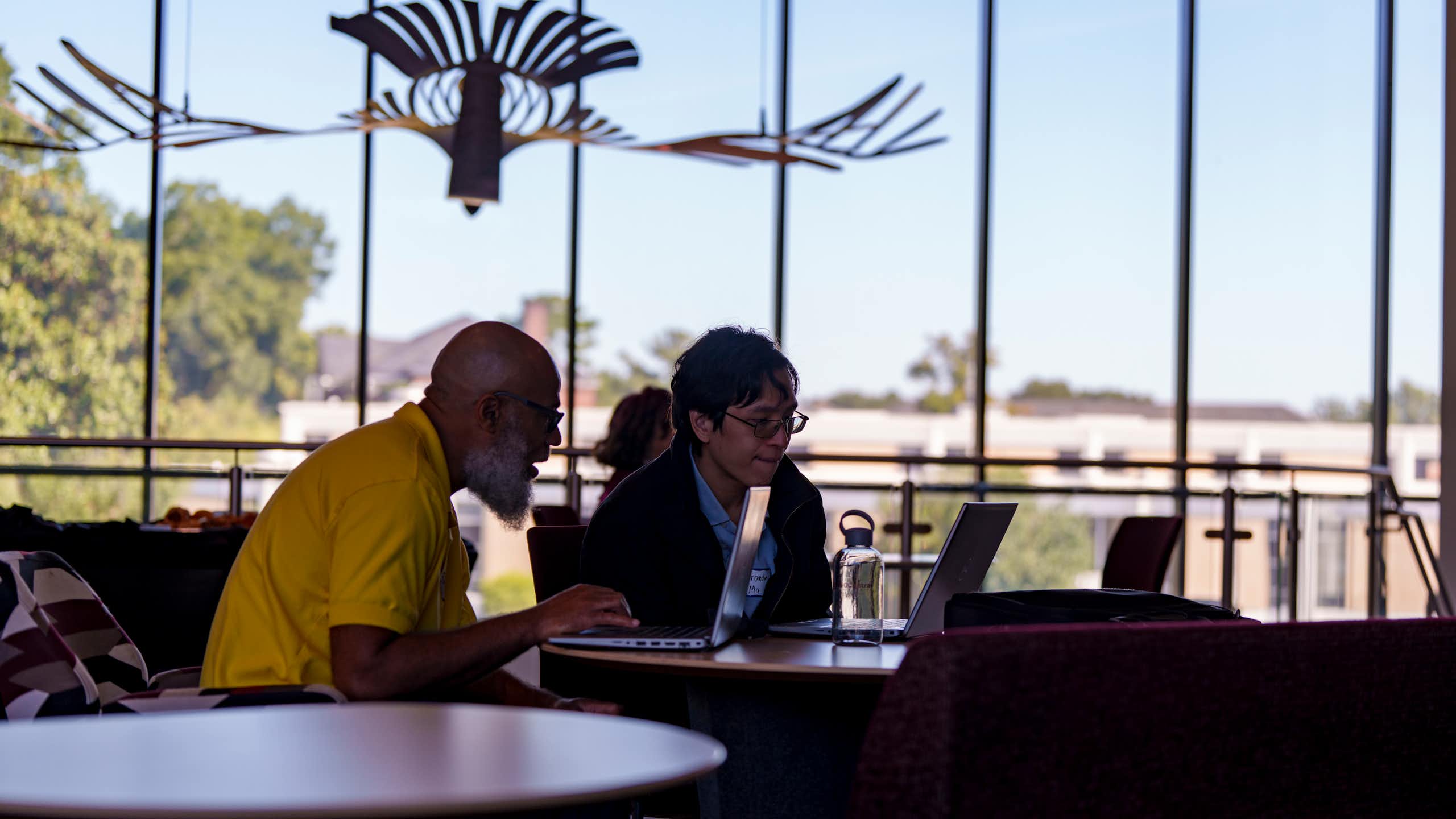 Two people looking at a laptop at the launch of new AI research center in North Carolina.