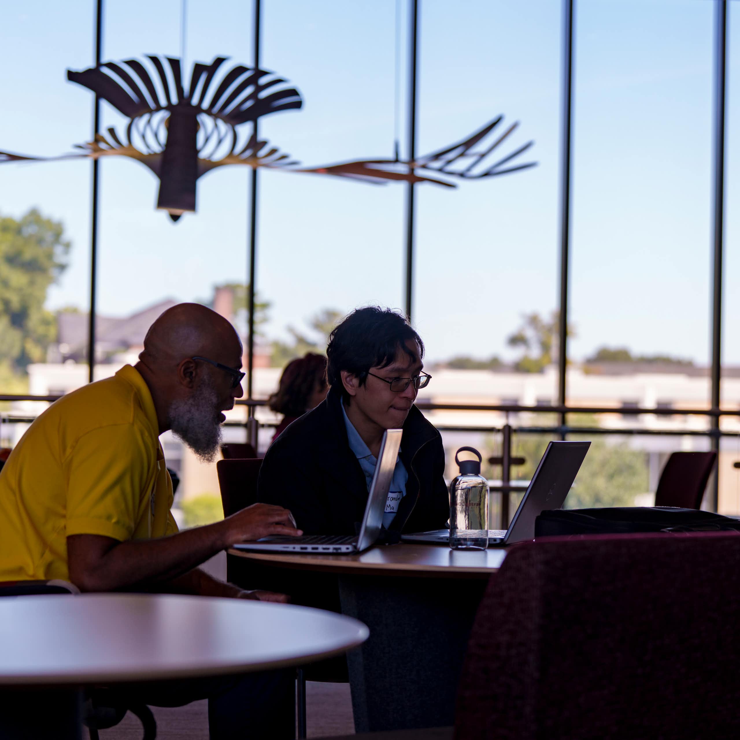 Two people looking at a laptop at the launch of new AI research center in North Carolina.