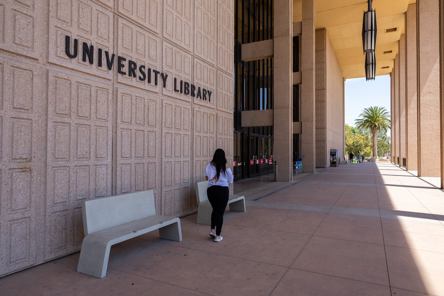 A student at California State University campus walks past a library.