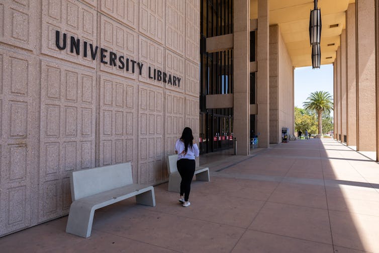 A student at California State University campus walks past a library.