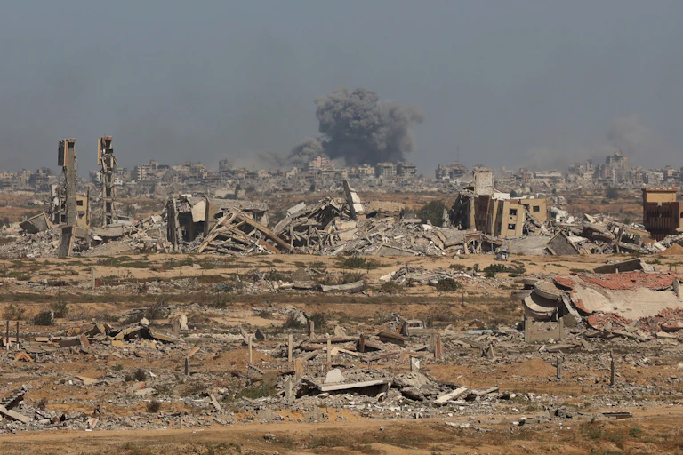Smoke billows above broken buildings..