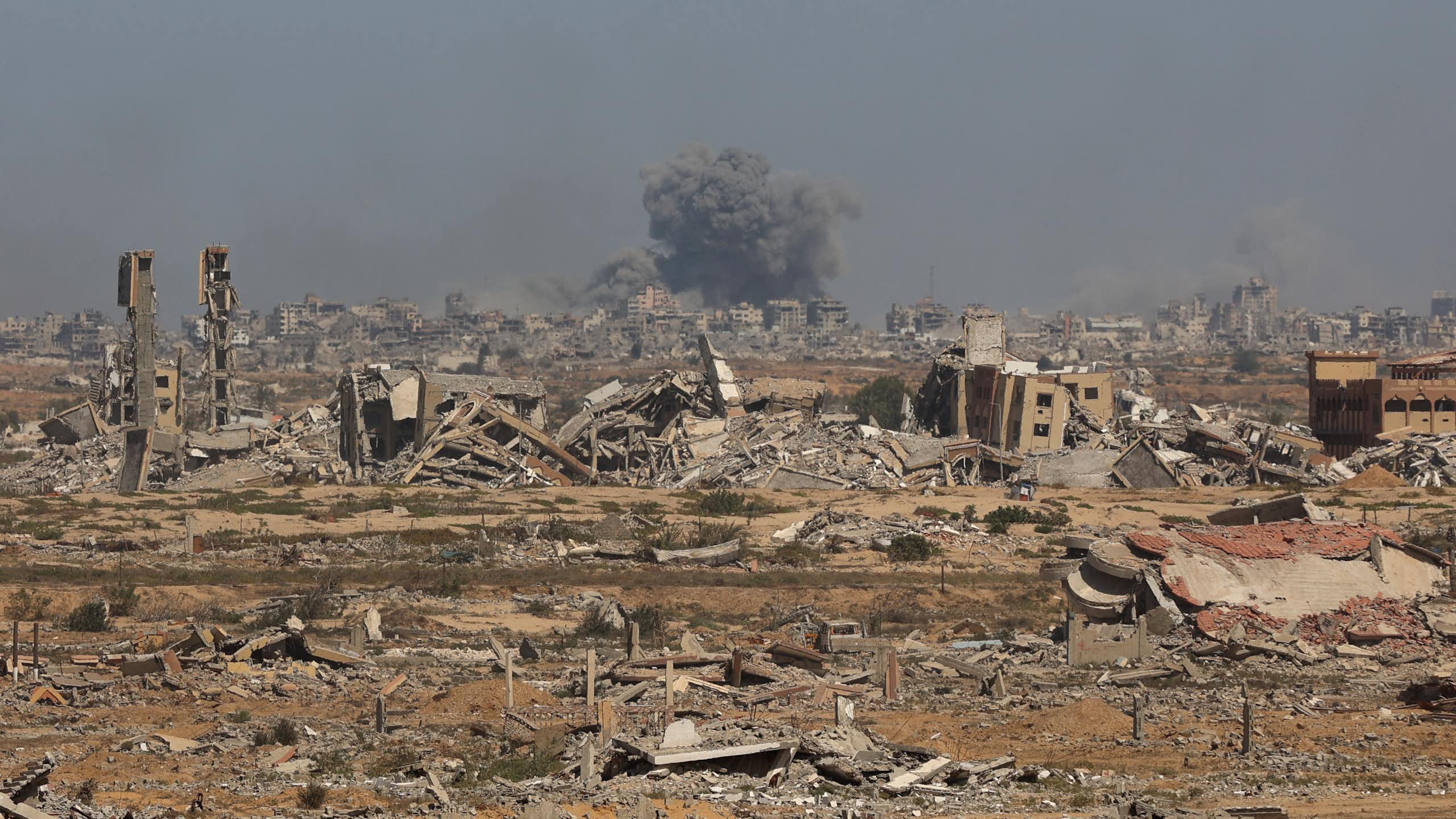 Smoke billows above broken buildings..