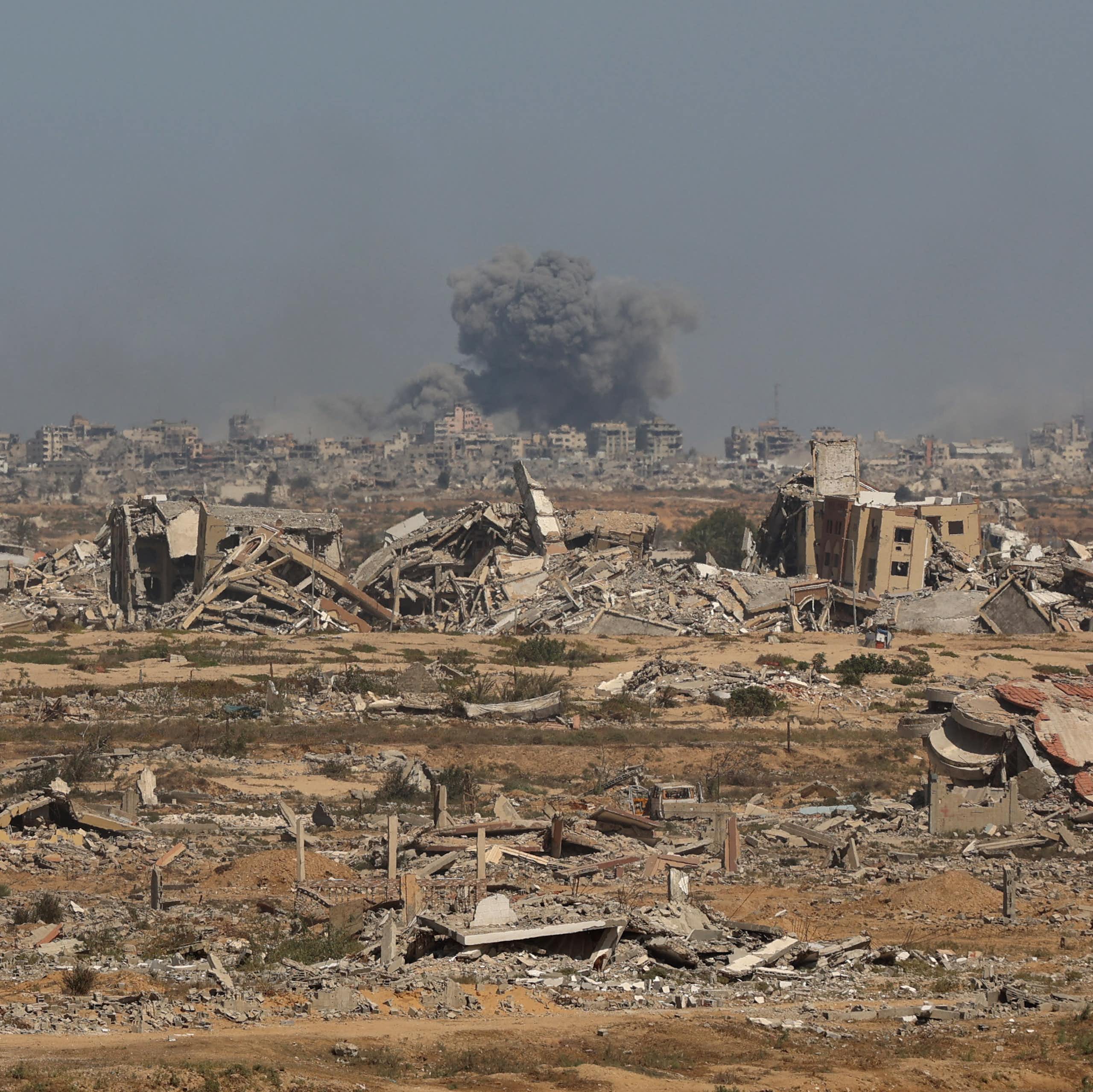 Smoke billows above broken buildings..
