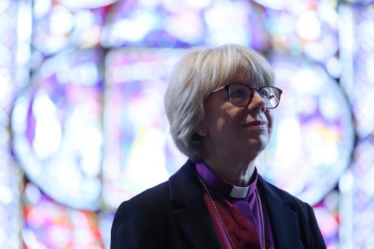 Mullally poses for a portrait in front of a stained glass window