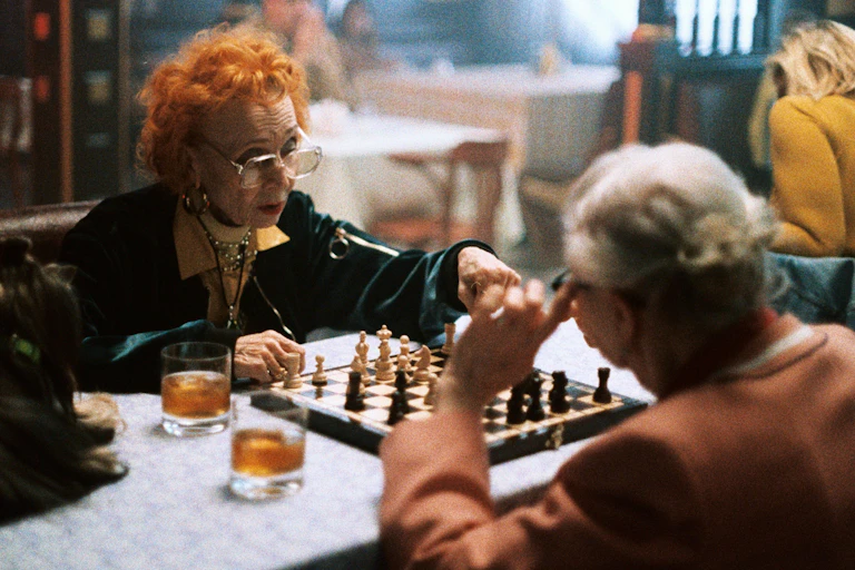 Two older women play chess.