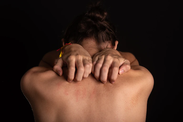 back of naked person, hands grabbing skin in pain
