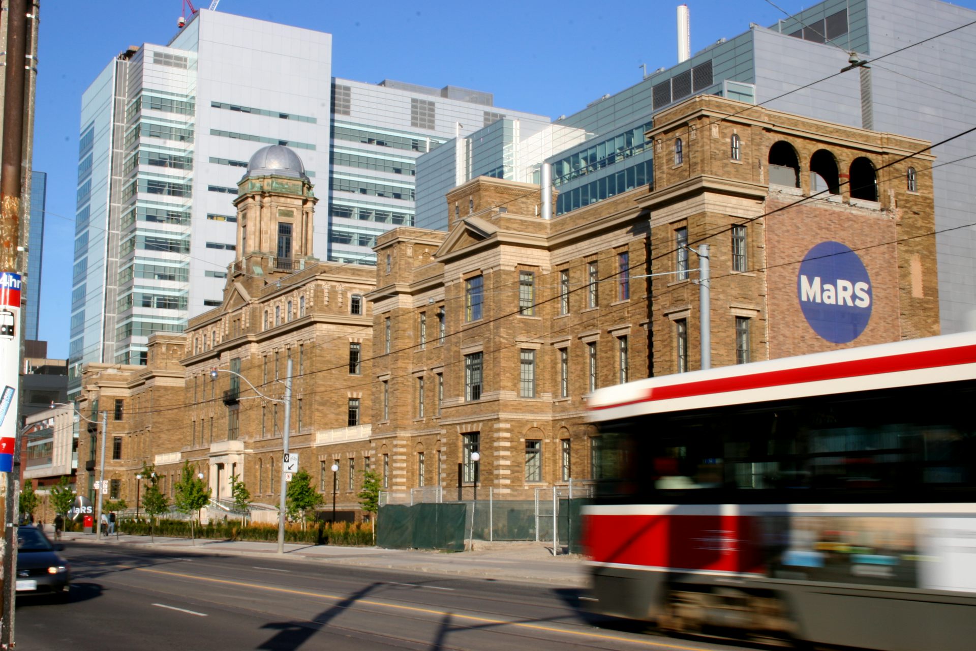 A streetcar goes past a building with the MaRS logo on it.