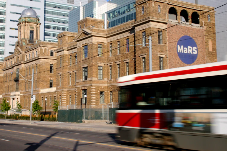 A streetcar goes past a building with the MaRS logo on it.