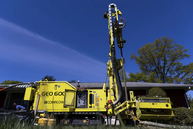A large yellow vehicle with a tall tower on it stands in front of a house.