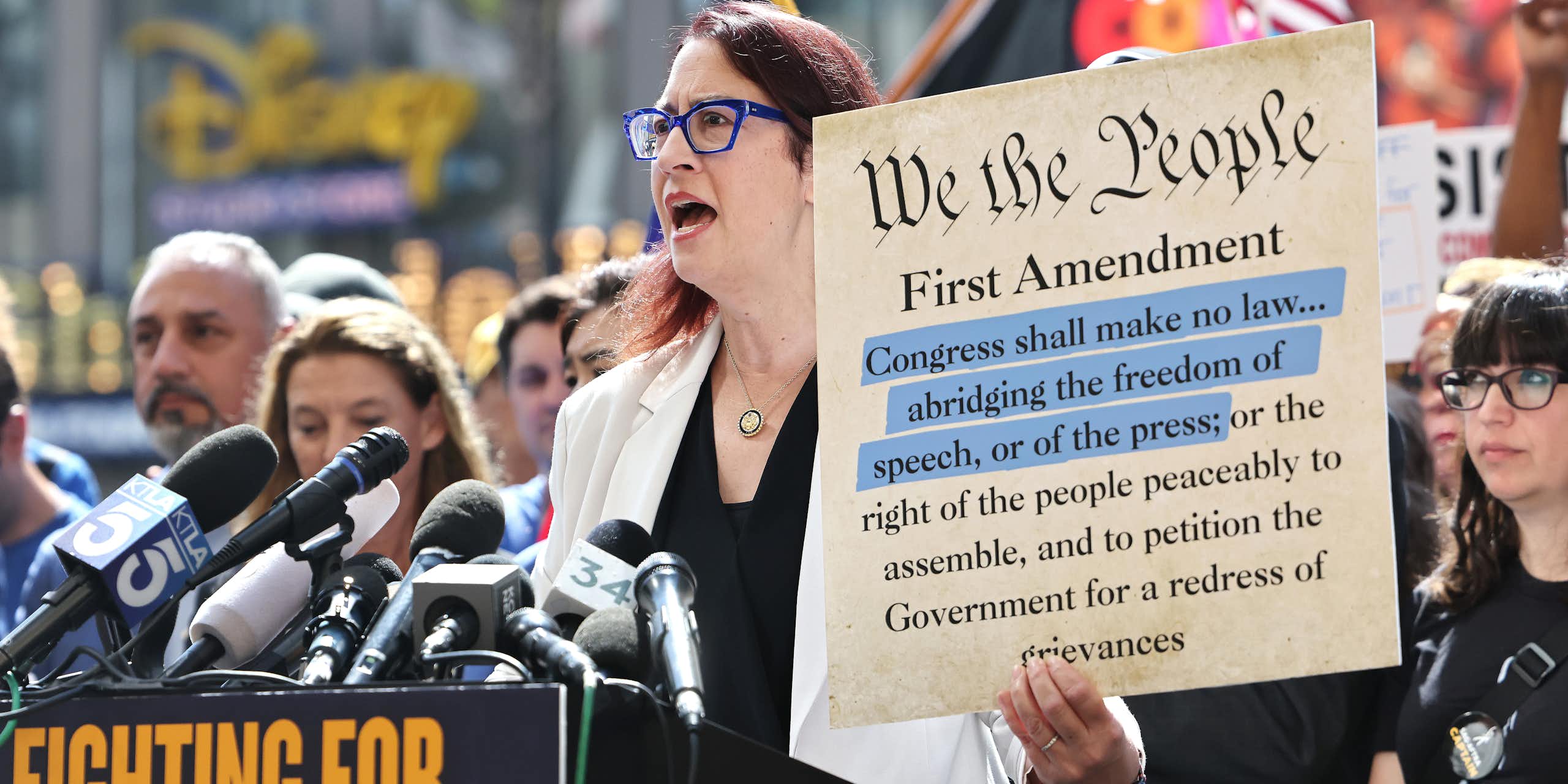 A group of people at a free speech protest, showing a copy of the First Amendment.