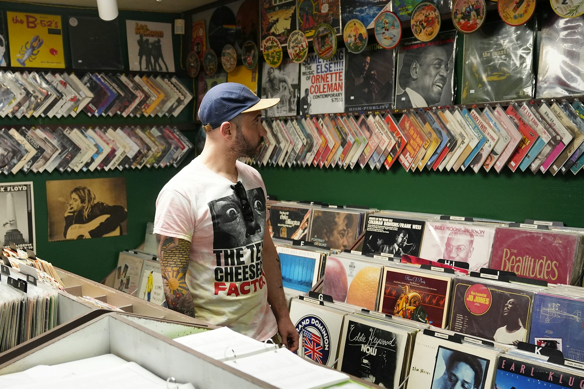 A person stands in a record store looking at records on the wall.