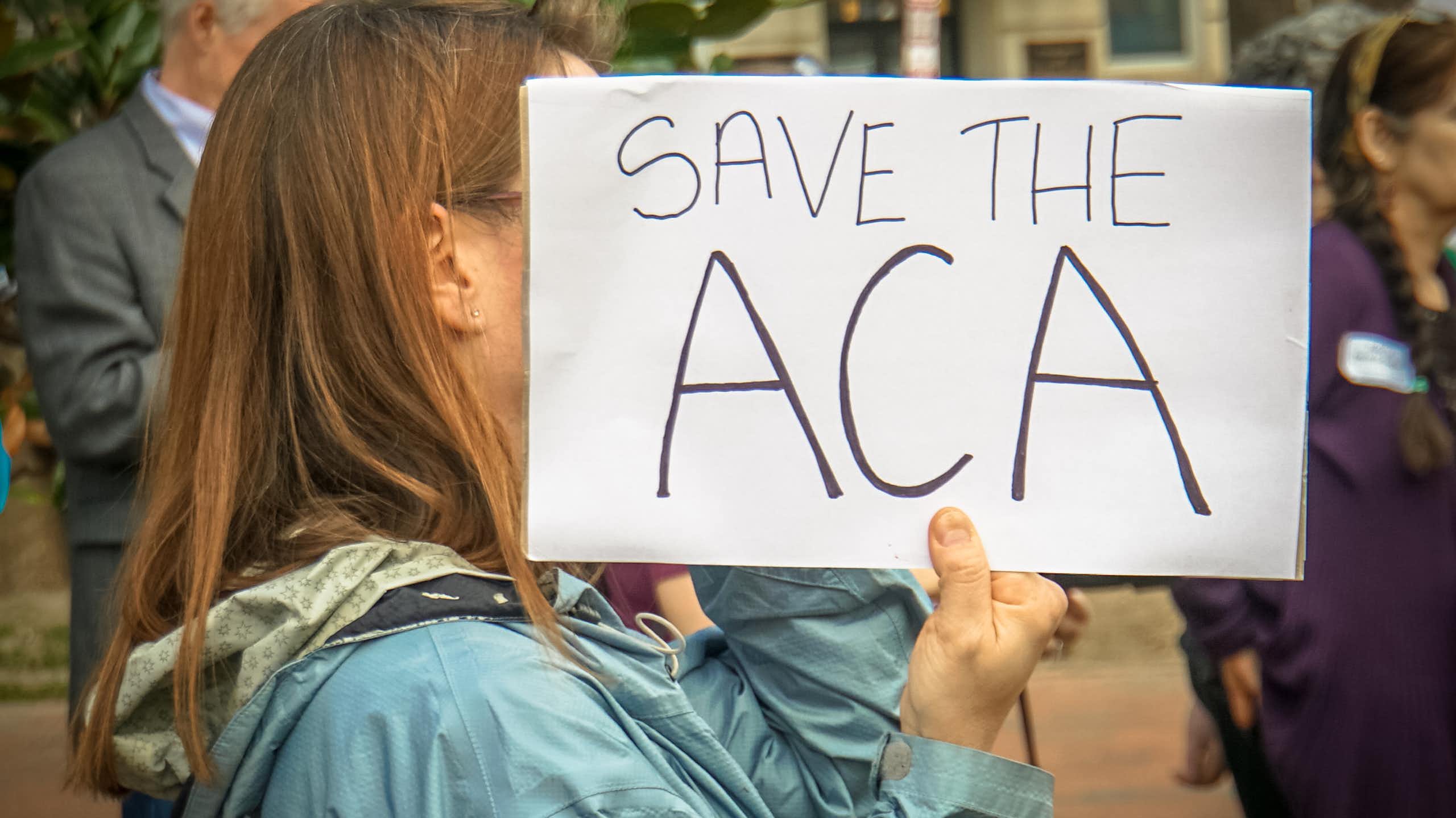 Person holding a sign saying Save the ACA