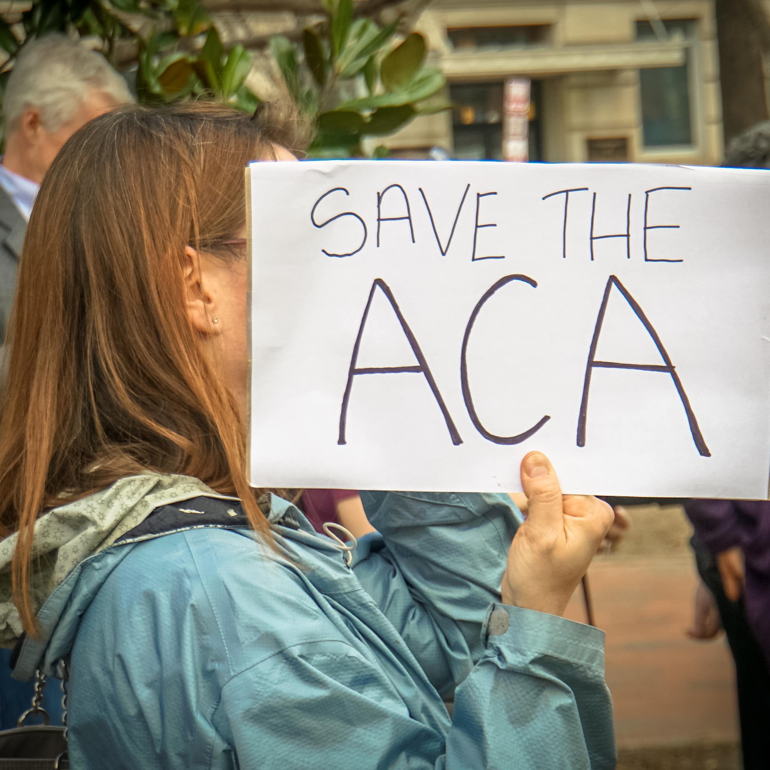 Person holding a sign saying Save the ACA