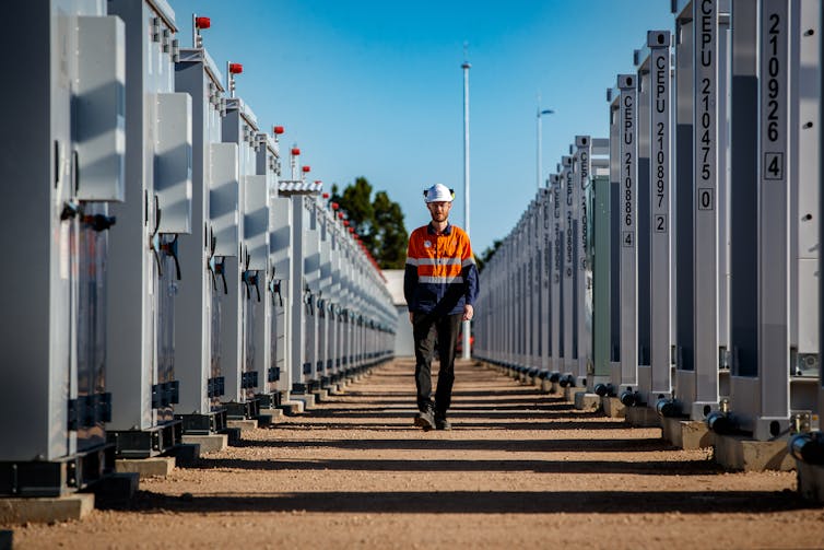 worker walking between large batteries.