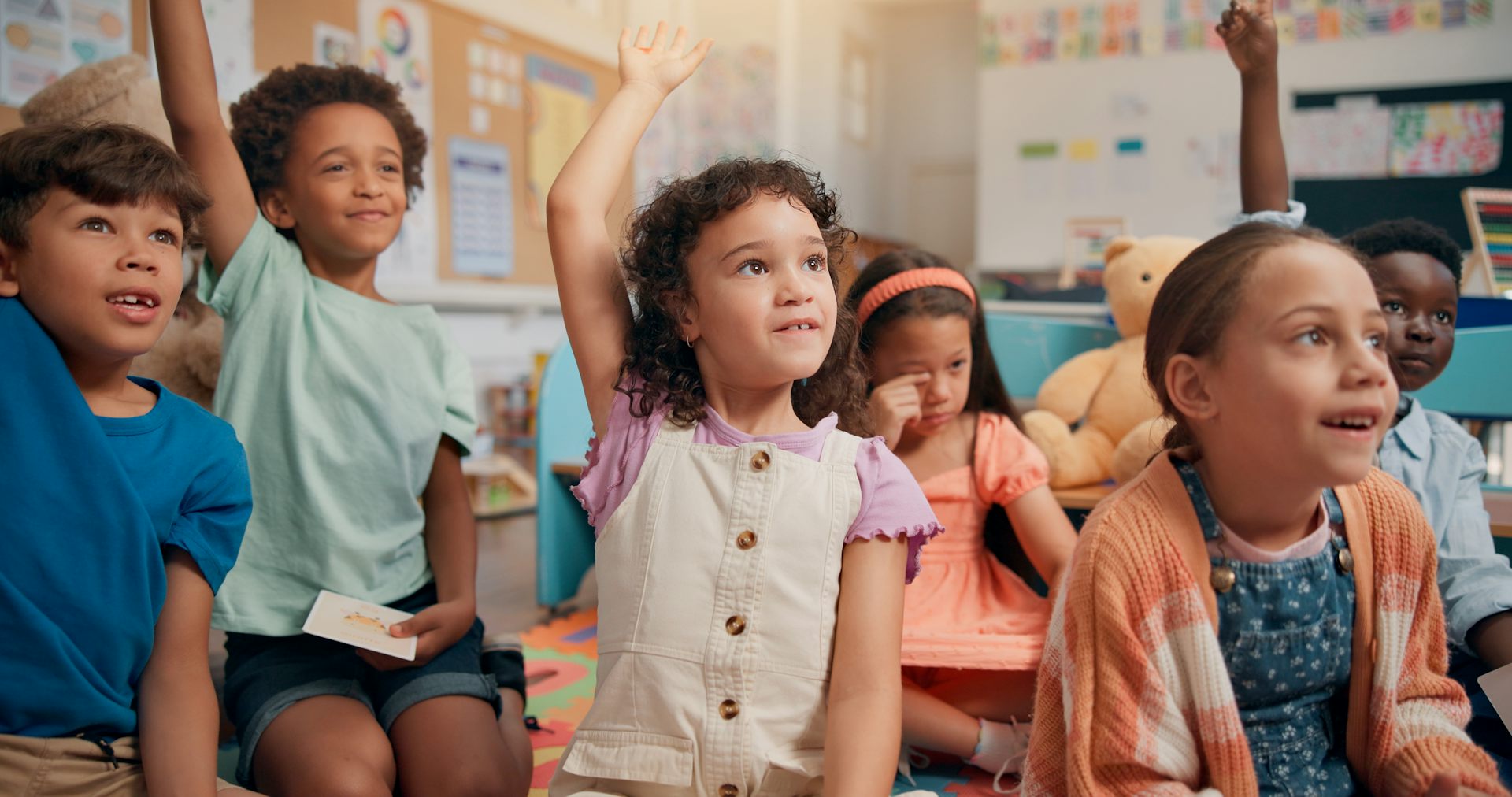 Small children raising hands in class