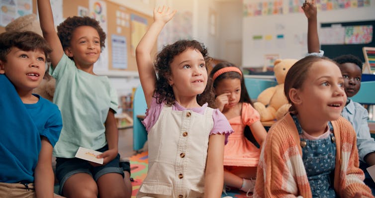 Small children raising hands in class