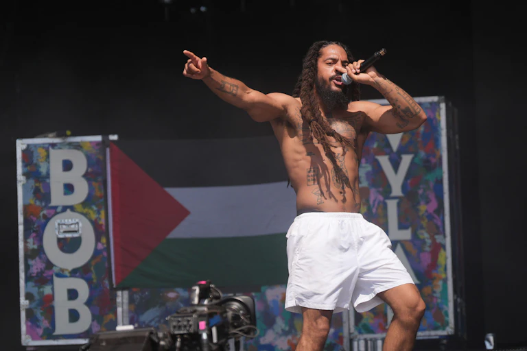 Bob Vylan onstage with a Palestine flag in the background