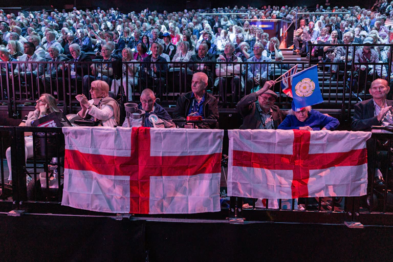 An audience of people sitting behind St George's flags.