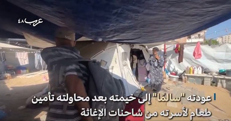 A Palestinian man carries a rucksack as he walks into a tent.