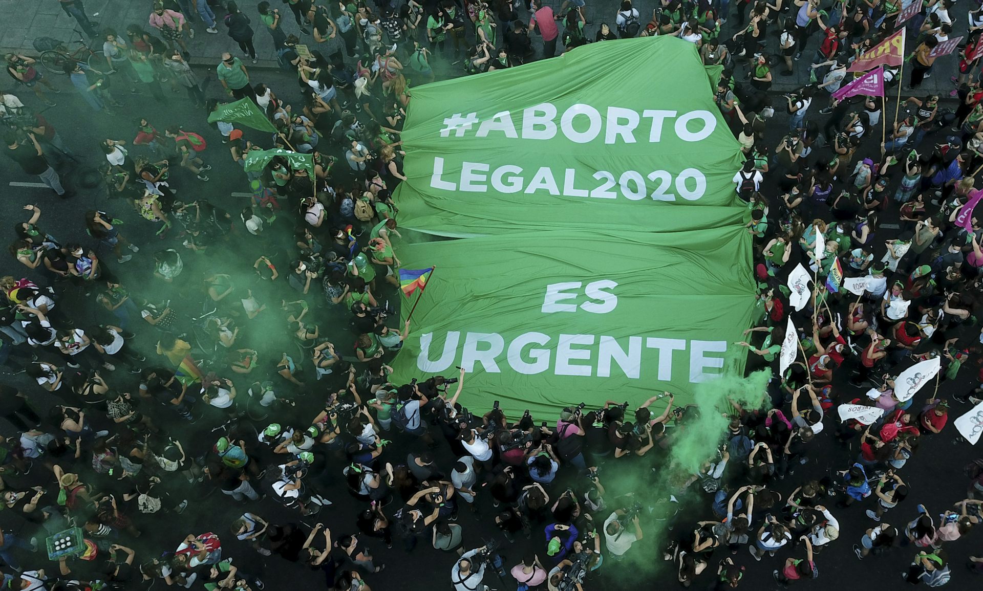 Aerial shot of a large crowd holding a banner reading 'aborto legal es urgente'