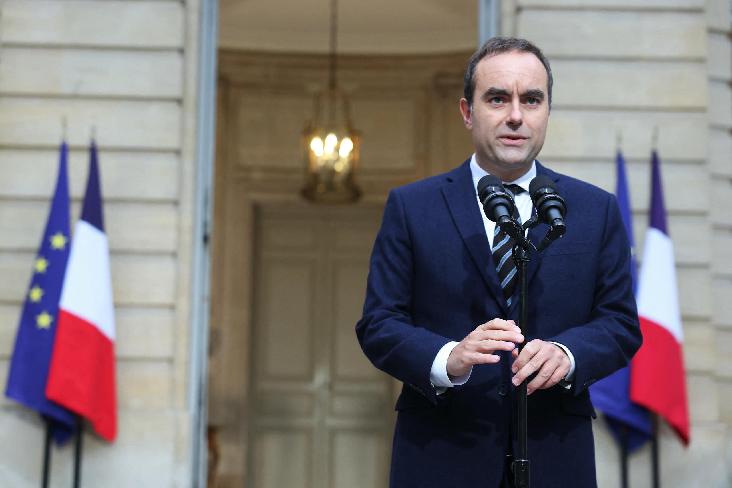 Wearing a suit and tie, French Prime Minister Sébastien Lecornu speaks in front of two microphones in daylight in front of a building.