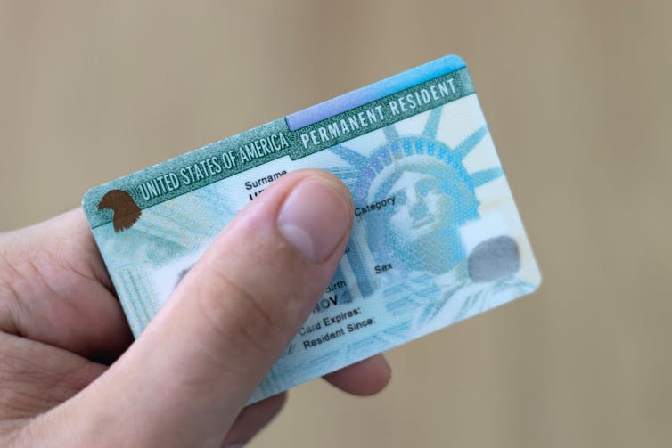 A hand holding a green card.