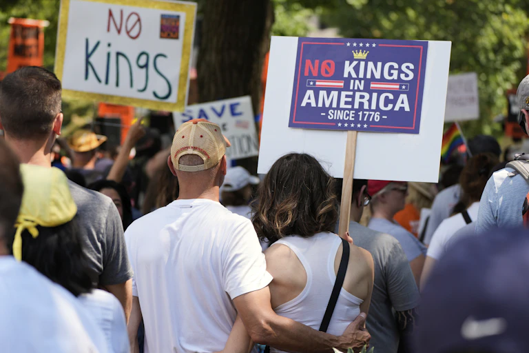 Protesters holding signs that say 'No Kings' and 'No King in America since 1776.'