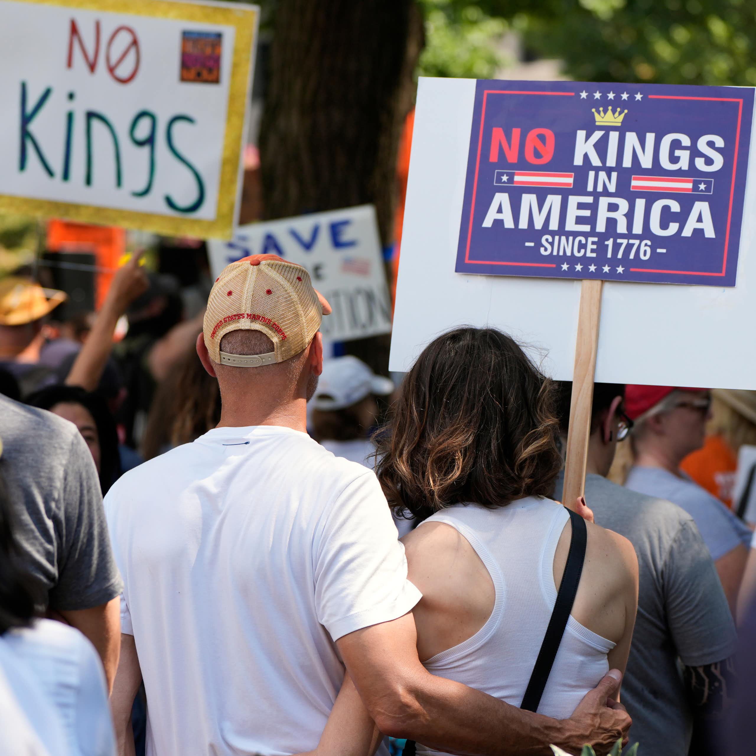 Protesters holding signs that say 'No Kings' and 'No King in America since 1776.'
