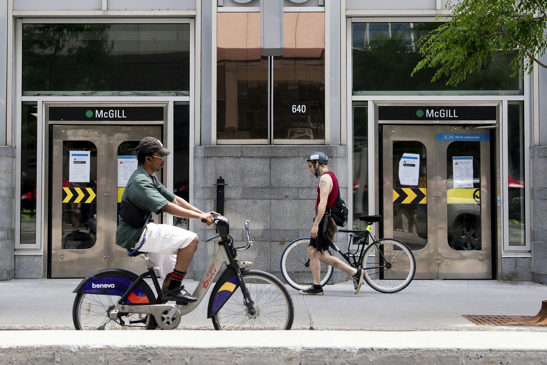 Des cyclistes circulent devant une bouche de métro