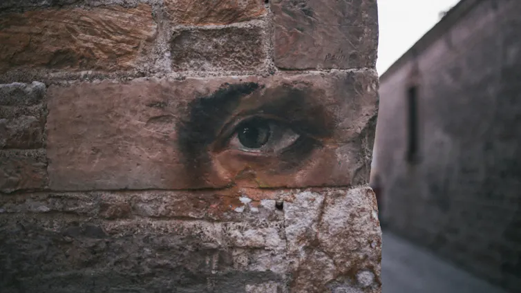An illustration of an eye on a brick wall.