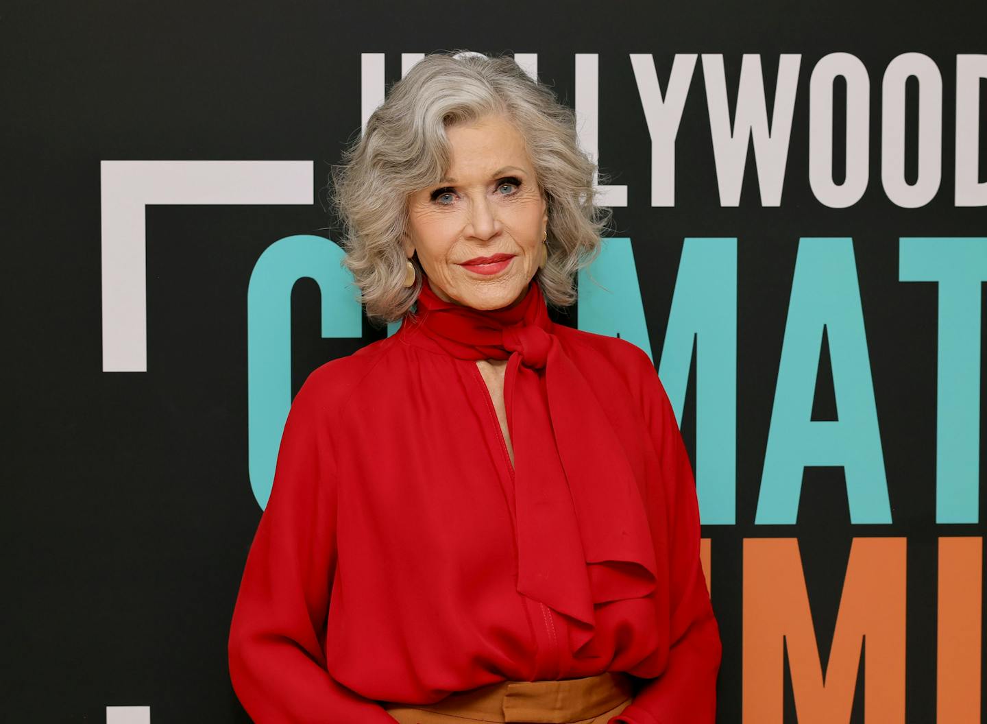 Jane Fonda looks at the camera against a backdrop that says 'Hollywood Climate Summit.'