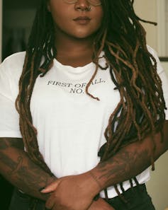 A Black woman in a t-shirt that says, 'first of all, no'