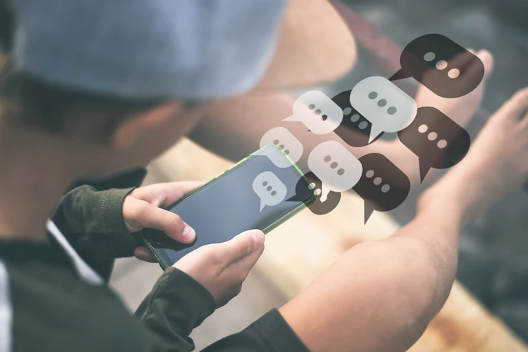 Un adolescent qui dialogue sur un smartphone.