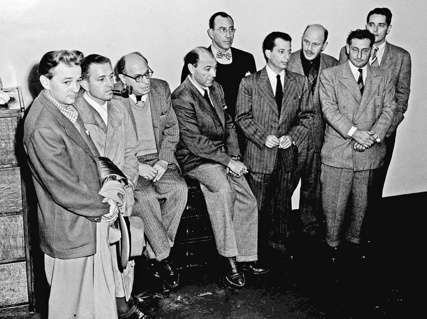 Ten men in suits stand together in a black-and-white photograph taken in the mid-20th century.