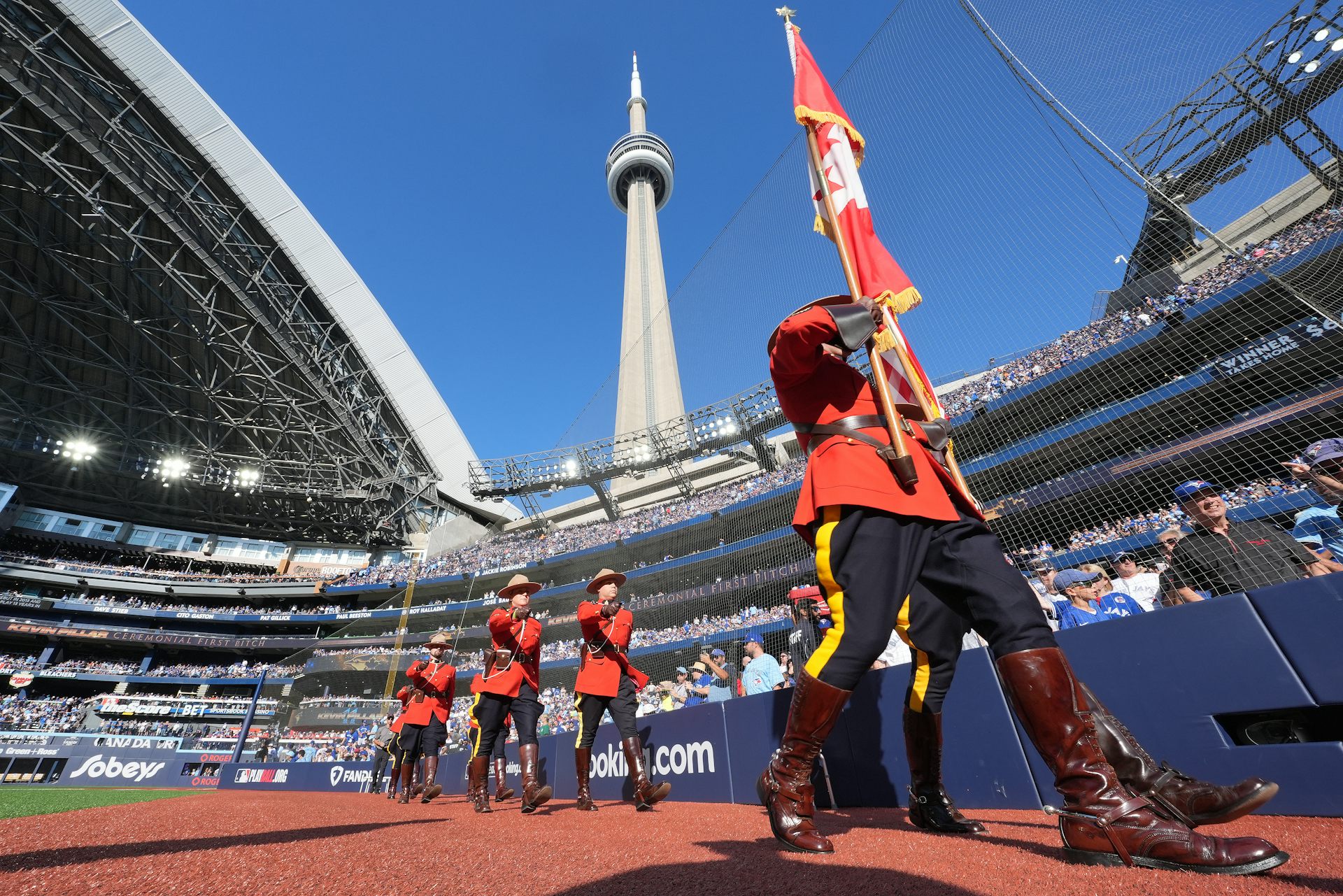 Mountrie en Red Coat Series lleva una bandera canadiense con montañas detrás de él y una torre CN que juega sobre él.