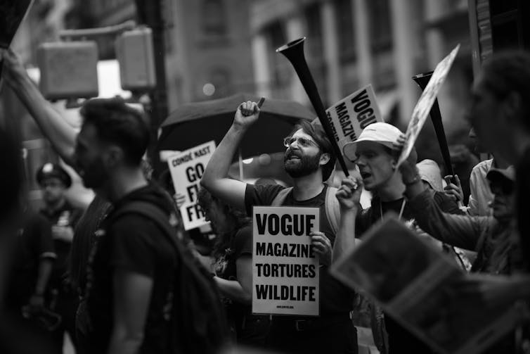 Individuals demonstrate against Vogue's use of fur.